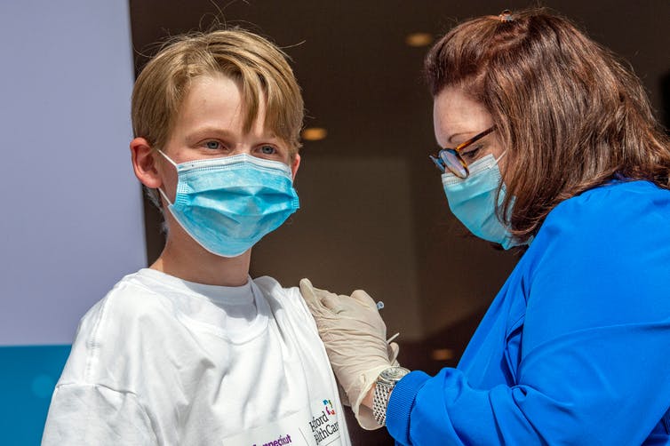 A teenage boy at a clinic getting a COVID-19 shot.