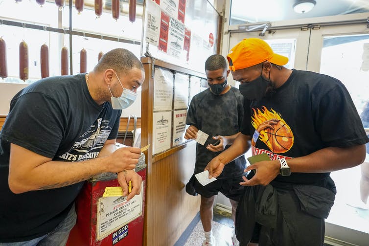 An employee of Katz's Deli in New York City looks down to inspect a customer's vaccination card