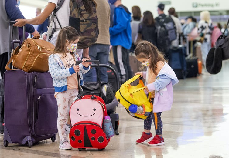 young girls masked at airport with luggage