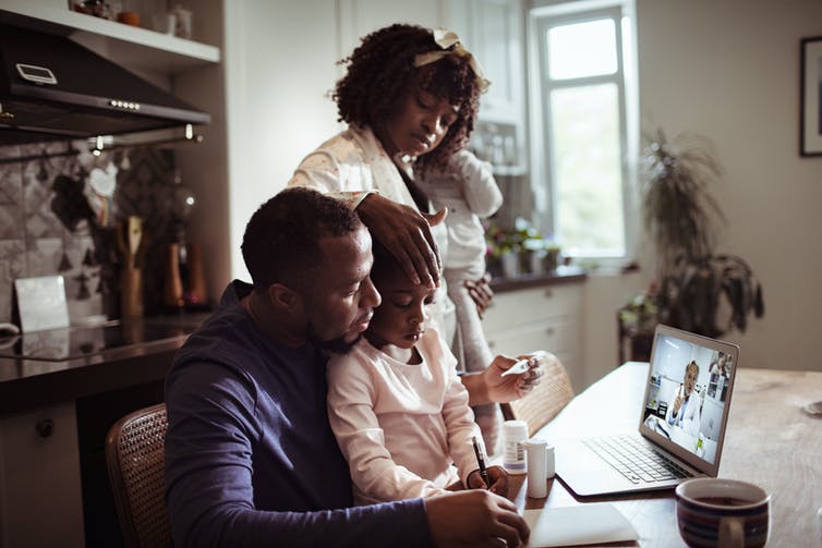 Family consulting with their doctor from the comfort of their kithen table via laptop.