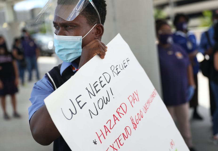 An unemployed airline worker holds a sign calling for an extension of federal benefits.