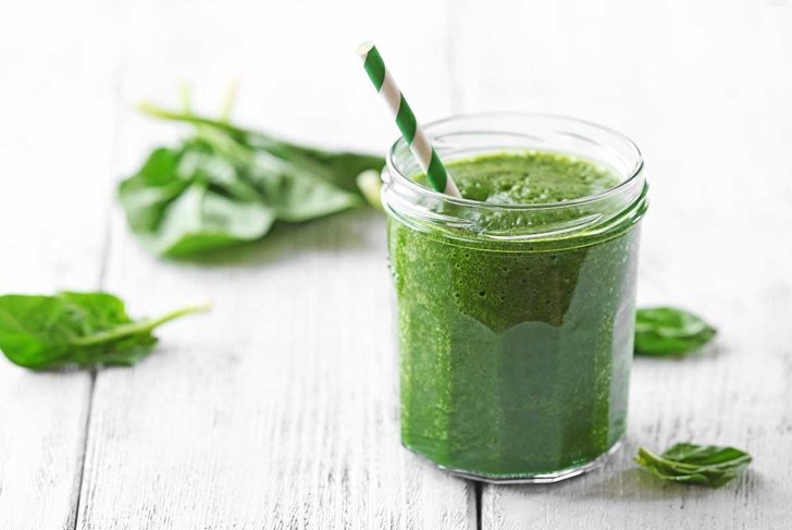 Glass of spinach juice on wooden background