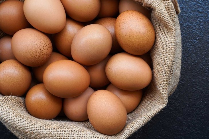 Chicken eggs in sack bag on black background.