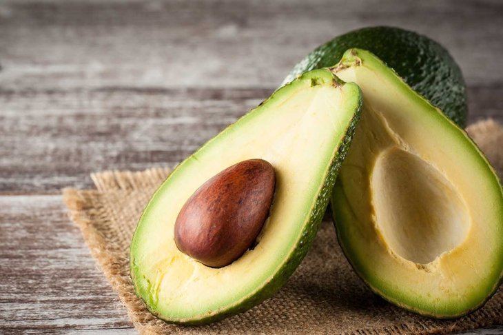 Close-up of an avocado and avocado oil on wooden table. Healthy food concept.